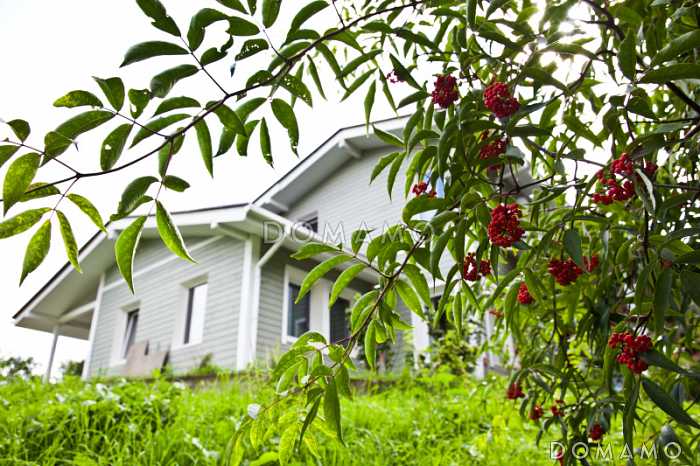 Проект дома из пеноблоков с навесом для машины и двумя спальнями на мансардном этаже