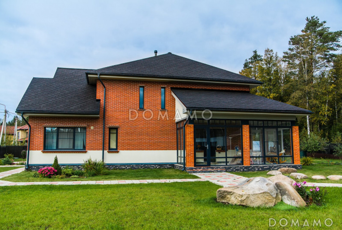 Проект кирпичного дома с панорамным остеклением на веранде, гаражом и навесом для авто